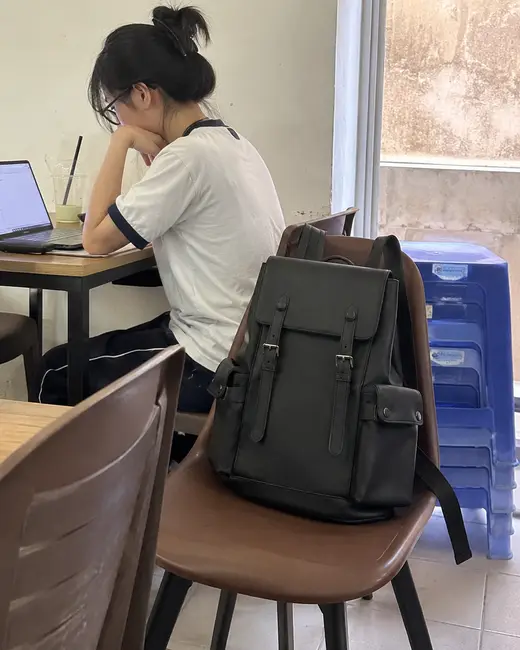 Balo Guardian màu đen đặt trên ghế cạnh bàn làm việc có laptop