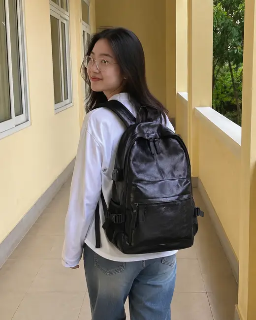 Bạn nữ đeo balo màu đen dáng vòm, đứng bên hành lang