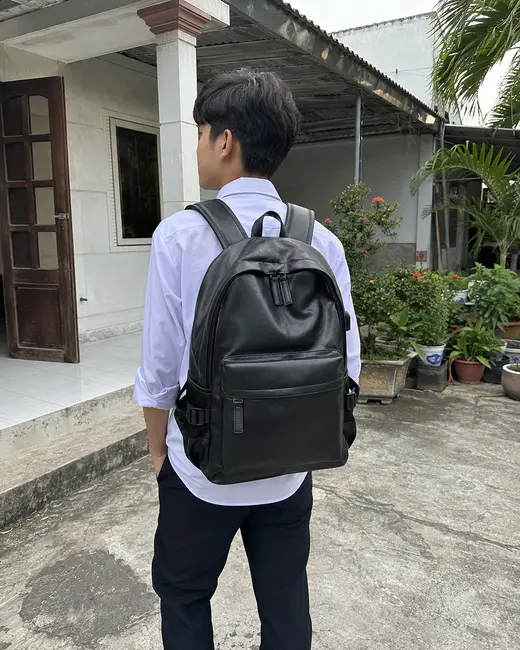 Bạn nam đeo balo màu đen dáng vòm trong sân