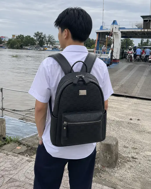 Bạn nam đeo balo họa tiết monogram đứng ở bến phà